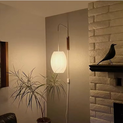 Wall-mounted lamp with a plant and bird decorative item in a room setting.