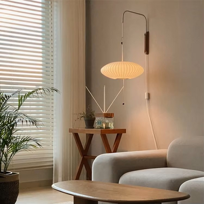 Modern living room with a wall-mounted lamp, plant, and sofa.
