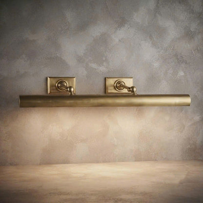 A brushed brass wall-mounted bathroom towel bar with two matching square backplates, shown against a textured beige plaster wall.