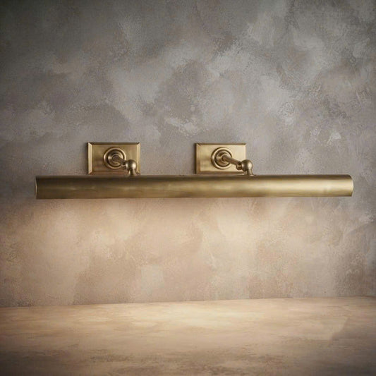 A brushed brass wall-mounted bathroom towel bar with two matching square backplates, shown against a textured beige plaster wall.