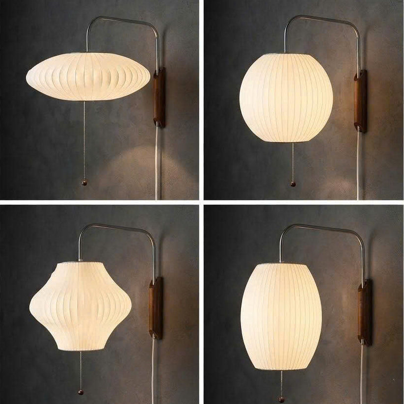 Four wall-mounted lamp designs shown in a 2x2 grid under the heading 'Product display.' Each lamp has a dark metal wall arm and shade, with shades in white, cream, and warm off-white tones against a dark gray wall.