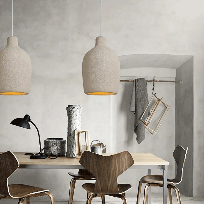 Three minimalist Wabi-Sabi stone pendant lights casting soft illumination over a sleek modern couch.
