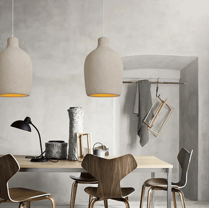 Three minimalist Wabi-Sabi stone pendant lights casting soft illumination over a sleek modern couch.