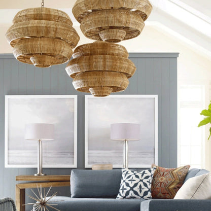 Tiered wicker drum pendant shade throwing a rich, multi-level golden glow through tightly woven sustainable rattan fibers.