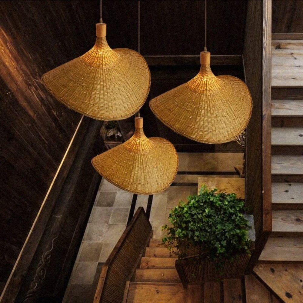 Wavy rattan sun hat pendant light hanging elegantly above a wooden dining table with a minimalist vase.