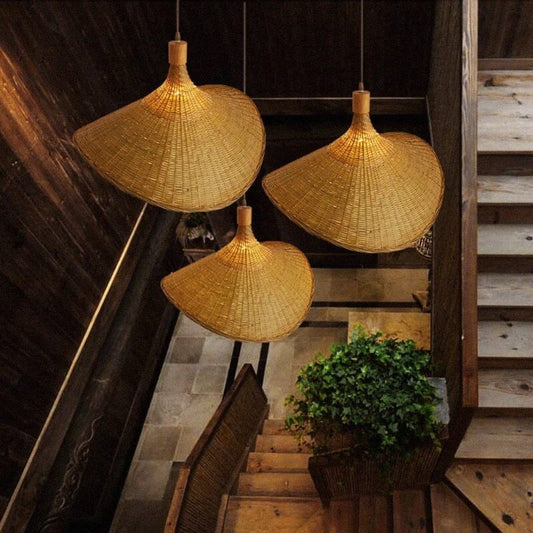 Wavy rattan sun hat pendant light hanging elegantly above a wooden dining table with a minimalist vase.