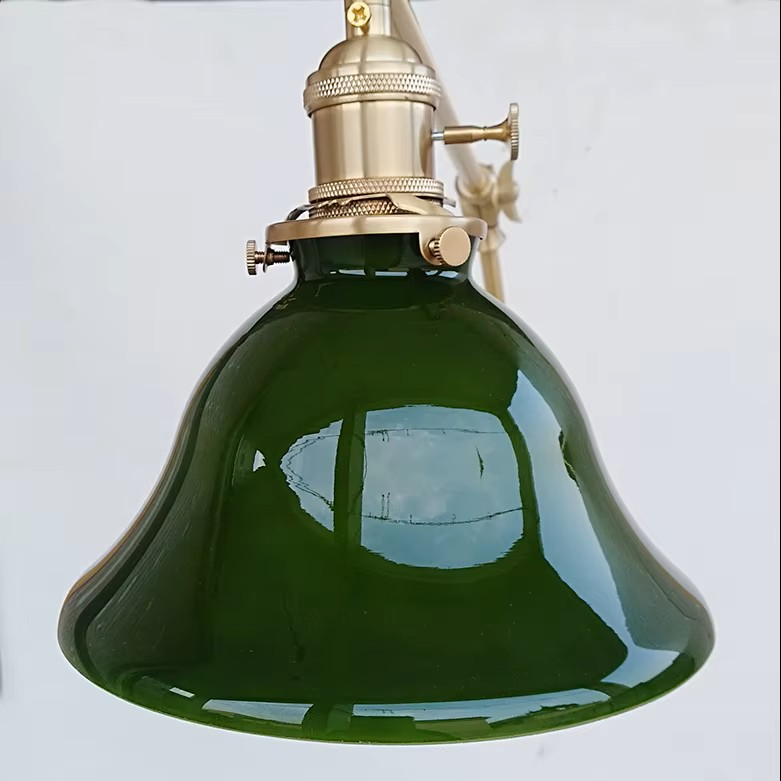 A vintage-style hanging lamp with a glossy dark green glass shade and a brass metal socket and cord hardware, shown against a plain white background.