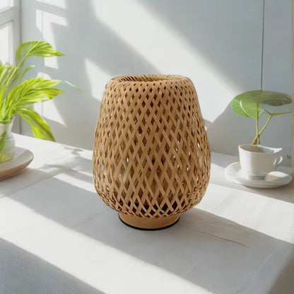 Woven rattan lamp on a white surface with plants in the background