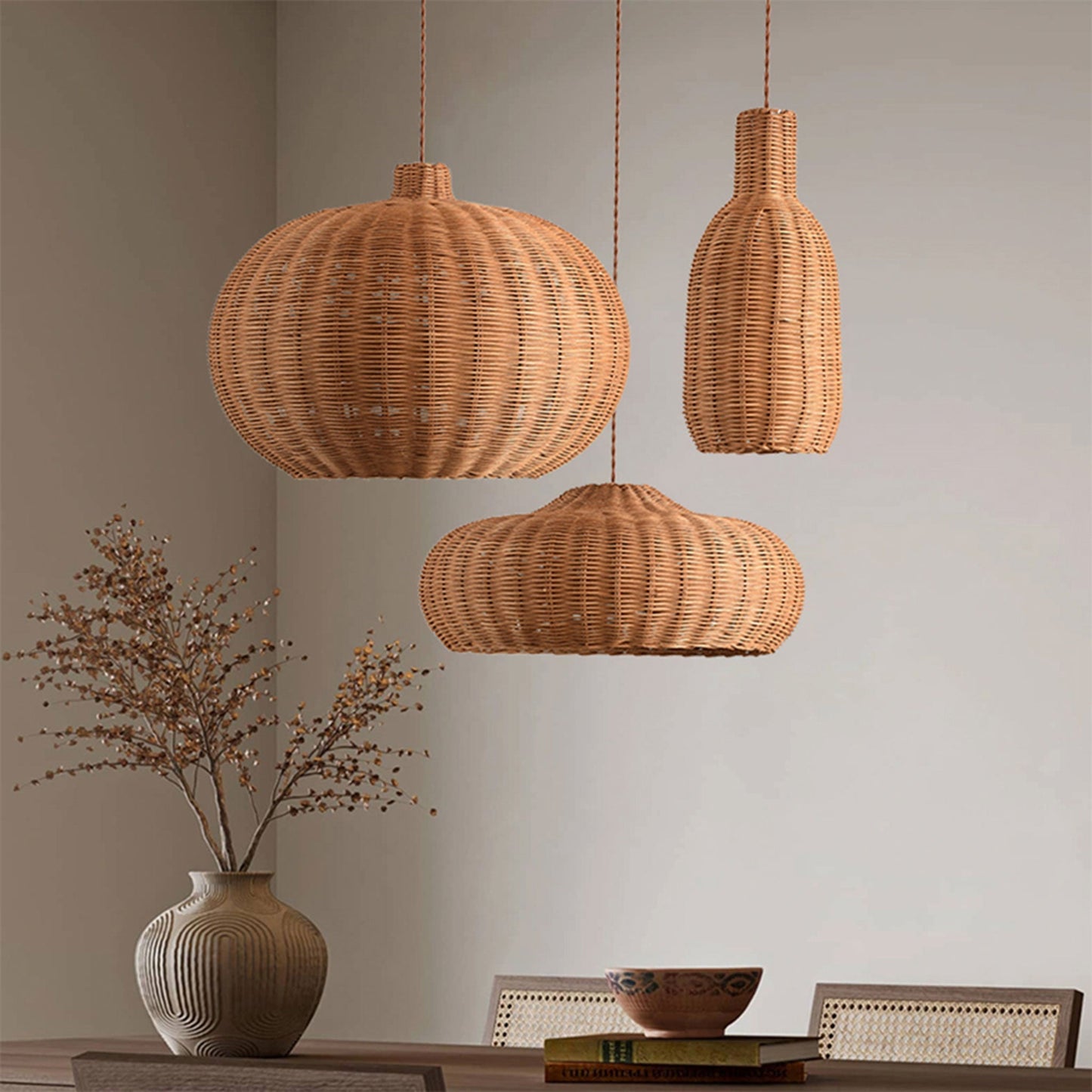 Three handwoven rattan pendant lights of different shapes hanging over a dining table.